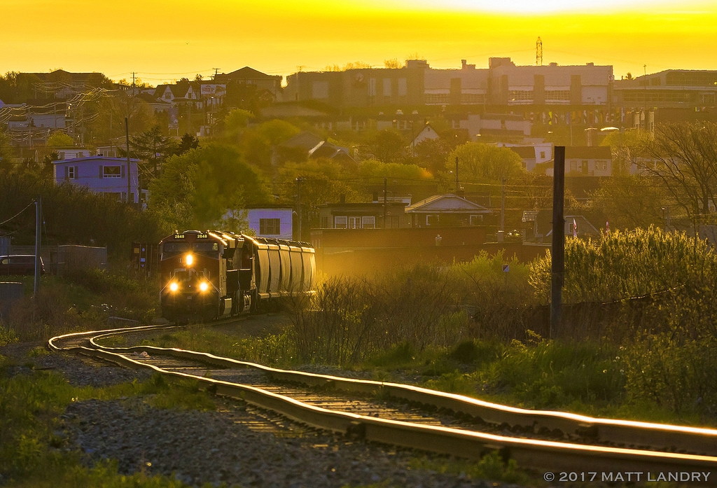 The tracks over to CN's Courtnay Bay yard are in rough shape. At sunrise, CN B730 slowly negotiates it's train around the "rock cut" and are on the move to set off the cars at Courtnay Bay to be unloaded. The tail end of the train is still in CN's Island Yard, blocking crossings with their slow journey over.