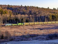 GMTX 2233 leads a New Brunswick Southern Railway "X907" empty woodchip train westbound at Clarendon, New Brunswick, with the rising sun shining some nice light along the chip cars. 