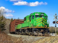 NBSR 2318 and NBSR slug 008 lead a massive train of 13 loaded woodchip cars eastbound, as they head through Welsford, New Brunswick. 