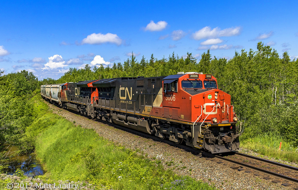 CN 3006 leads an eastbound potash train, as they approach the Trans Canada Highway at Berry Mills, west of Moncton, New Brunswick.