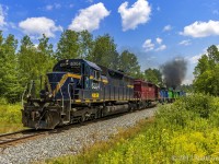 With a couple of Geeps putting up a smoke show on the rear of the consist, NBSR westbound train 907 crosses the "Dirt Road", mile 52 of the McAdam Sub.