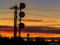 Under a fiery sunrise, the signal at the west end of Amherst is lit for CN Q120's arrival, who are a few miles away. 