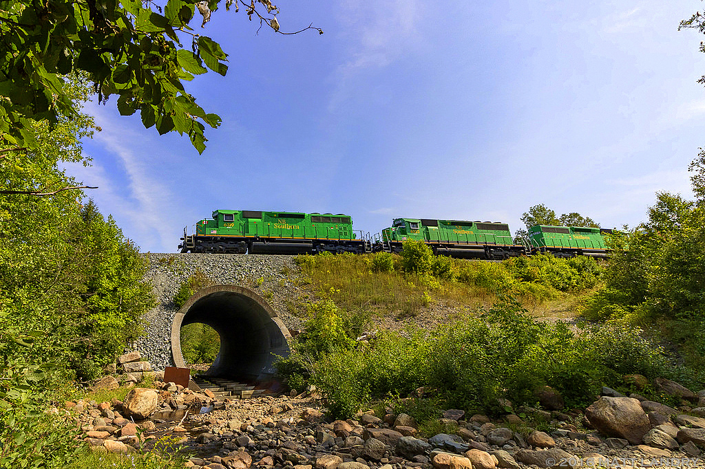 Plenty of green in this shot, as NBSR 6319 leads a New Brunswick Southern Railway westbound freight, as they head through Grand Bay, New Brunswick.