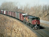 Twenty-one years ago this area looked about like it does today. Barren lands of spring; golf course is off to the left and quarry lands off to the right; giving this location an 'out in the sticks' appearance. This is actually almost into the city. I am standing on the Portage Rd overpass, looking at an eastbound (at this point)running train, a mile or so before the Stamford Sub split and a bit farther away than that to the former location of CN NF yard.
Nice consist, which is why I am out this morning; CN 2107, WC 6618 and GT 6417. The lead unit, a BBD HR616, part of a fleet of 20 acquired by CN in 1982, proved to be an annoyance at best, and the whole bunch were gone from CN by 1998. This particular unit went to NRE.