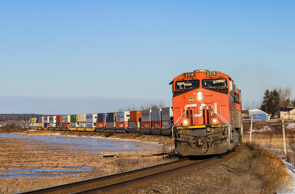 Running about 3 hours late, CN Q120 rounds the S curve at Upper Dorchester, New Brunswick, shortly after the sun finally makes it's way over the horizon along the Memramcook marshes.