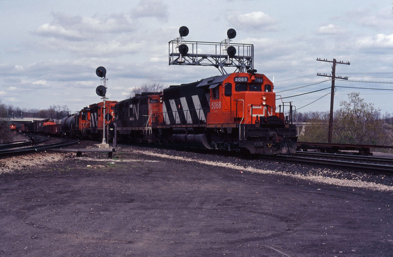 A CN westbound crosses from the South Track to the North Track at Bayview, heading for Hamilton and Niagara behind SD40 5068, GP9s 4526 and 4530, and SW1200RS 1259. In the background, another westbound is about to tackle the hill to Copetown and southwestern Ontario.