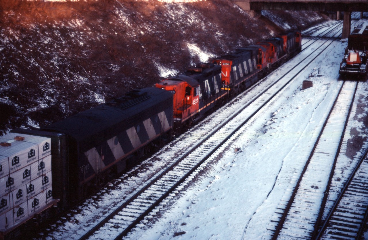 An eastbound passes CN's Hamilton station on its way to Niagara (likely Fort Erie). Power on the train is (from furthest to nearest unit) CN GP40-2LW 9502, an unidentified RS18, C630m 2030, GP9 4525, and F7Bu 9195. While still used as a passenger station, at least four of the six tracks at the James Street North station are now devoted to freight car repairs and track six holds a maintenance of way crane.
