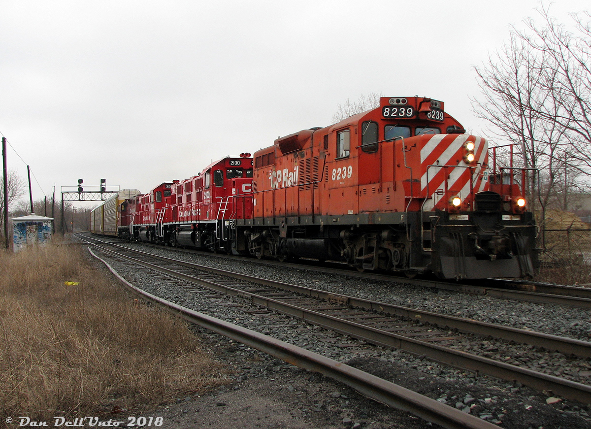 1950's durability teams up with 2000's tech: Canadian Pacific GP9u's 8239 and 8215 bracket nearly new NRE 3GS21B Genset locos 2100 and 2101, slamming Davenport Diamond eastbound on the North Toronto Sub with the usual transfer run #T56 (the Lambton-Agincourt Yard transfer run) and a sizable train on the drawbar. I was in the area enjoying an overcast and slightly rainy day and saw the train off in West Toronto Yard waiting to depart. I figured it was a pair or trio of SD40-2's, so expectations weren't really high. But sure enough, half an hour later the crossing gates go off and a pair of surprises show up trailing. This was shot from the old private crossing between the former Canadian General Electric Royce Works and Davenport Works plants that were under redevelopment at the time (and even though the crossing roadway was ripped up, the gates and signals were still perfectly functional).

CP was trying out a variety of different options to replace their aging fleet of 1950's 4-axle Geeps in the 2000's. First was the ill-fated "Green Goat" battery powered units made from rebuilt Geeps (they were a big flop). Next was this pair of "Genset" locomotives from National Railway Equipment that operated in local and transfer service (equipped with three small diesel engines instead of one larger one). While other roads seem to be happy with theirs, they failed to meet CP's performance expectations and were stored and returned to NRE with little fanfare. In the end, CP opted for the EMD GP20C-ECO program that saw hoards of their old GP9u's "rebuilt on paper" (meaning sent for scrap with truck frames, compressors, etc re-manufactured and used in the construction of new GP20C-ECO units built on new frames). A few lucky GP9 units including 8239 and 8215 managed to last long enough in local service to escape the trade-in program, and were instead declared surplus and sold off to shortlines, industrial operators and leasers.

But, the old gals did manage to outlast those newfangled Gensets.