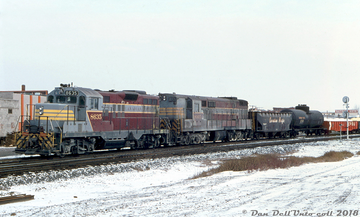 CP GP9 8635 and H24-66 "Train Master" 8905 work Alyth Yard in Calgary AB with a cut of cars. An unusual pairing, but quite regular: there were three GP-TM sets assigned to work the Alyth Yard hump in the mid-70's until the final three big TM's were retired. How this all came about was an interesting story:

The biggest of the big at the time when it hit the market was the Fairbanks Morse H24-66  "Trainmaster". Powered by a 12-cylinder 24-piston opposed-piston 38D8 1/8 engine making 2400 horsepower. CP purchased one unit as a test from FM-CLC (8900) in 1955, followed by 20 more units (8901-8920) built under license by the Canadian Locomotive Company in Kingston ON in 1956. Early on they were run between Calgary and Revelstoke, with a few being based out of Toronto and Montreal in transfer service for a while. Over time larger, more powerful and more reliable power came onto the scene, and due to reliability problems CP's MEchanical Department decided to begin retiring all their Train Masters in 1966. Eight units were scrapped (with traction motors going to MLW for use in new C630M's 4500-4507), and six were sold to a Marine supply outfit in the US for salvaging of their opposed-piston engines (popular in marine use) and other components. The few remaining units were gradually wittled down to a few remaining in Calgary and Montreal transfer service (retired and scrapped early 70's), and 8900, 8904 and 8905 which found themselves assigned to heavy transfer work around the Cominco smelter in Trail BC in the early 70's. From there, they migrated to hump service in Calgary in mid-1973 (after the Eastern Region made it absolutely clear they *did not want them*, having retired the last ones that remained in Montreal transfer service). Maybe CP couldn't afford to retire the last three just yet, what with the upswing in traffic and having to lease all sorts of foreign power like hoards of ex-QNSL Geeps from Precision National and old B&O F-units.

Meanwhile, in 1970-1971 three GMD GP9 units (8633, 8634 and 8635) were given low short hoods by Ogden Shops as a test for better visibility, intended for use on the Alyth hump and yard assignments. Contrary to popular belief, they were not repainted in three separate schemes (action red, script, and block lettering respectively) - thrifty CP just did the mods, repainted that front area, and left each in the paint it came into the shop with. Dynamic brakes were removed, and each was done with modern GM-style numberboards and windows and a new "pointed" short hoods (all likely fabricated in-house by CP shop forces). The old hoods were actually removed and kept by CP as spares (there's a photo of 8633's short hood in action red stripes sitting on a flatcar at Alyth in 1972). Further GP9's got short hoods as they were rebuilt after wrecks or incidents, and it was incorporated into the rebuilt program for all remaining GP7, GP9 and RS18 units in 1980 (by then the existing short hoods were "chop-nosed" or cut down shorter, rather than having new hoods fabricated).

Initially the newly minted yard Geep trio ran on the hump with spare SW1200RS units in GP9-SW-SW pairings (the SW's were becoming too small for some of the heavier trains and larger cars being run), but then the aforementioned three remaining Train Masters from Trail made their way into hump service, where they were paired in three GP-TM sets until the order came down to park the TM's in late 1975 (they were poorly maintained by then, and one of the complaints was exhaust fumes were getting sucked into the yard office buildings). The order came down to retire the three for good in mid-1976. 8900 & 8904 were scrapped, but 8905 was retained by CP for preservation purposes. and currently resides at Exporail/CRM in Delson QC as the last Train Master in existence. GP-F7B-GP pairings at Alyth hump then became the norm, usually using older GP7 and GP9 units downgraded to yard service and old F7B's running out their final years before retirement.

Photographer unknown, slide from the Dan Dell'Unto coll.