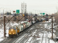 CN 310 with leased unit CREX 1510 leading passes under a signal bridge by one of the entrances to Taschereau Yard on a cloudy morning. Operating mid-train is another leased unit, GECX 2034.