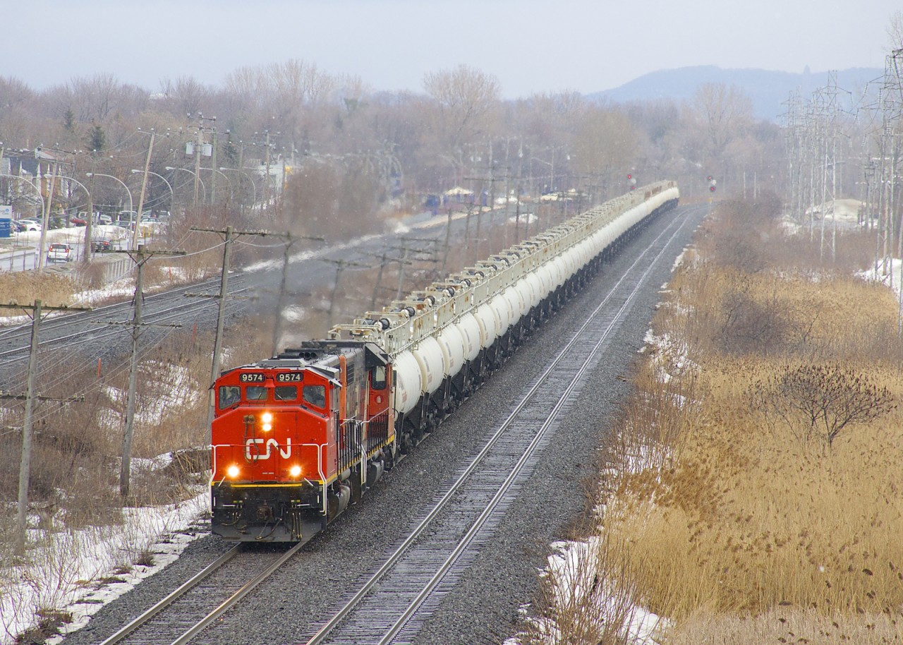 CN 9754 & CN 4729 lead CN 585 west through Pointe-Claire on a slightly snowy morning. The train has three strings of seventeen TankTrain cars, with fuel for an Ultramar facility in Maitland, Ontario.