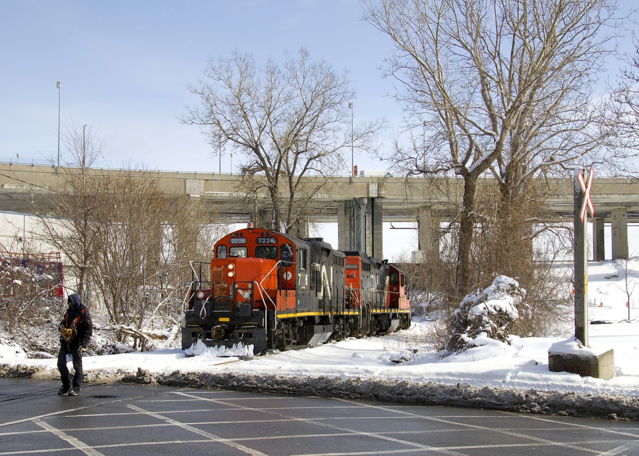 A crewmember is about to flag the Monk Boulevard crossing before the Pointe St-Charles switcher continues west on the Turcot Holding Spur, which branches off of CN's Montreal Sub at MP 4 and serves a pair of clients at the end of the line, a short distance away. GP9's CN 7226 & CN 7075 will pick up some empties at Kruger and then head to the East Side Canal Bank.