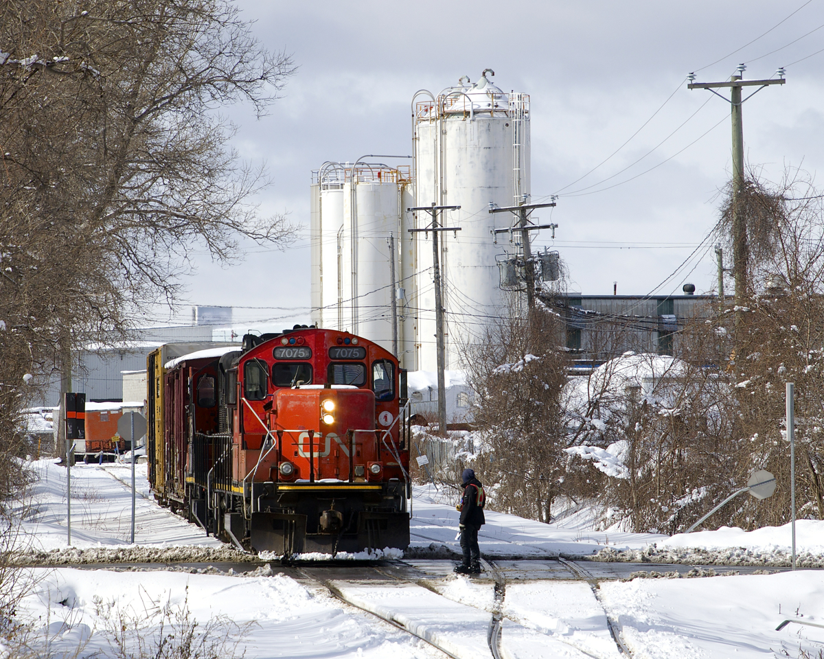 After flagging Monk Boulevard, a crewmember is about to climb back onto CN 7075 as the Pointe St-Charles Switcher leaves the Turcot Holding Spur with two boxcars in tow.