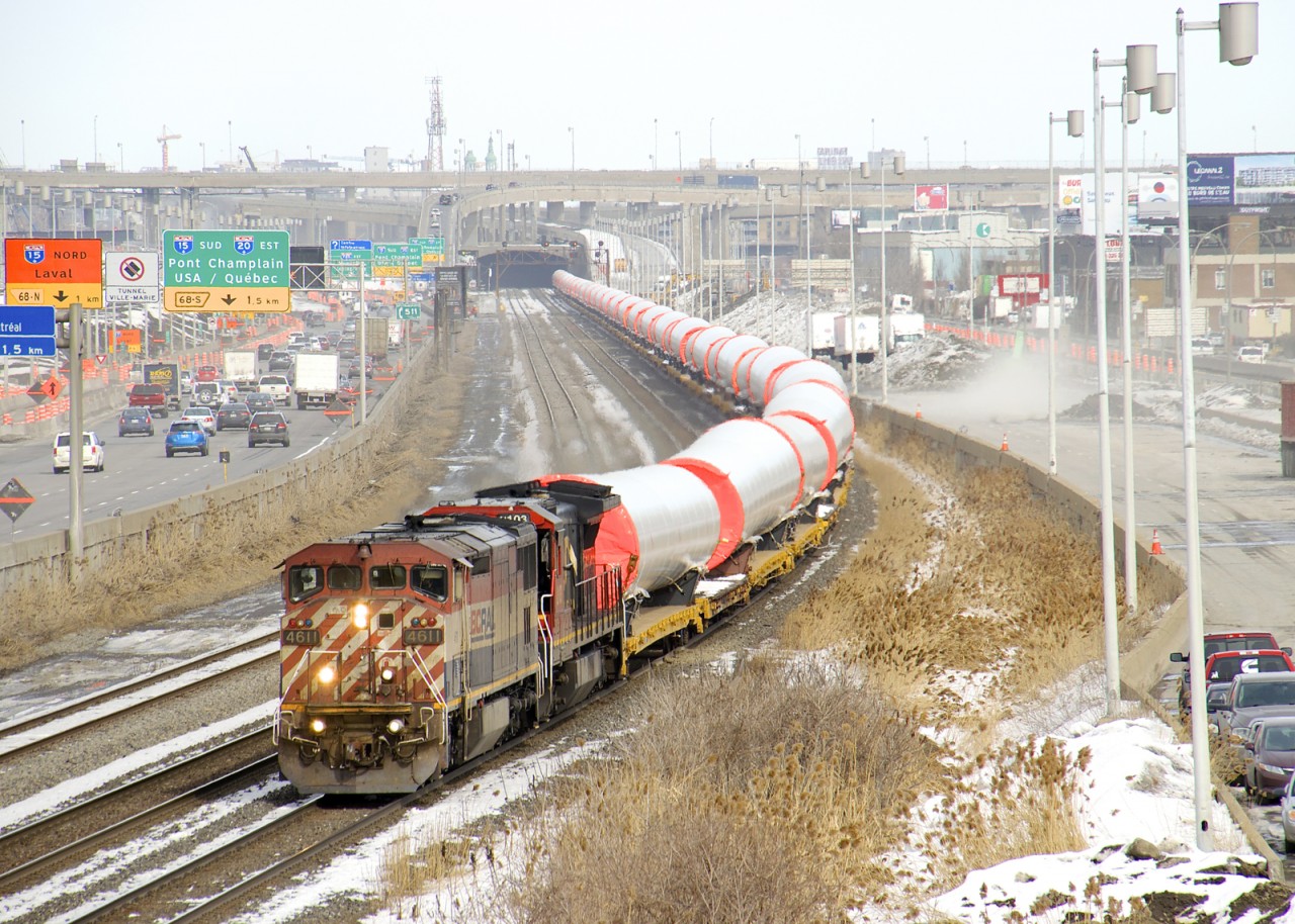 Windmill train CN L307 has 50 windmill towers spread over 75 cars as it approaches a crew change Turcot West with Dash8's BCOL 4611 & CN 2103 for power. This train will be handed off to the BNSF at Eola and are destined for Garden City, KS. At right work continues on dismantling the westbound lanes of autoroute 20.