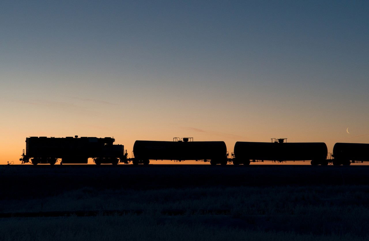 A clear day dawns on the prairies just as a crescent moon sets. In the foreground GMTX 2212 waits to begin another day of spotting tank cars to be loaded with oil.