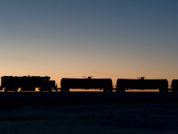A clear day dawns on the prairies just as a crescent moon sets. In the foreground GMTX 2212 waits to begin another day of spotting tank cars to be loaded with oil.   