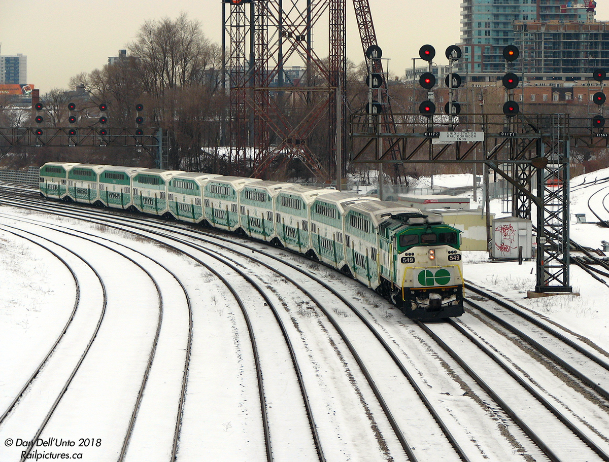 The hum of natural-gas fired switch heaters keeping the switch points clear of snow and debris blurs with the din of morning rush-hour traffic on the bridge, serving as background noise to the constant stream of morning GO, VIA, Amtrak and ONR trains click-clacking through the switches at Bathurst Street interlocking inbound to the city. Here, F59PH 549 leads packed Lakeshore West train #472 eastbound off the CN Oakville Sub into the Union Station Rail Corridor at Bathurst St., just a few minutes before 8:00am and just a few clicks away from its destination.