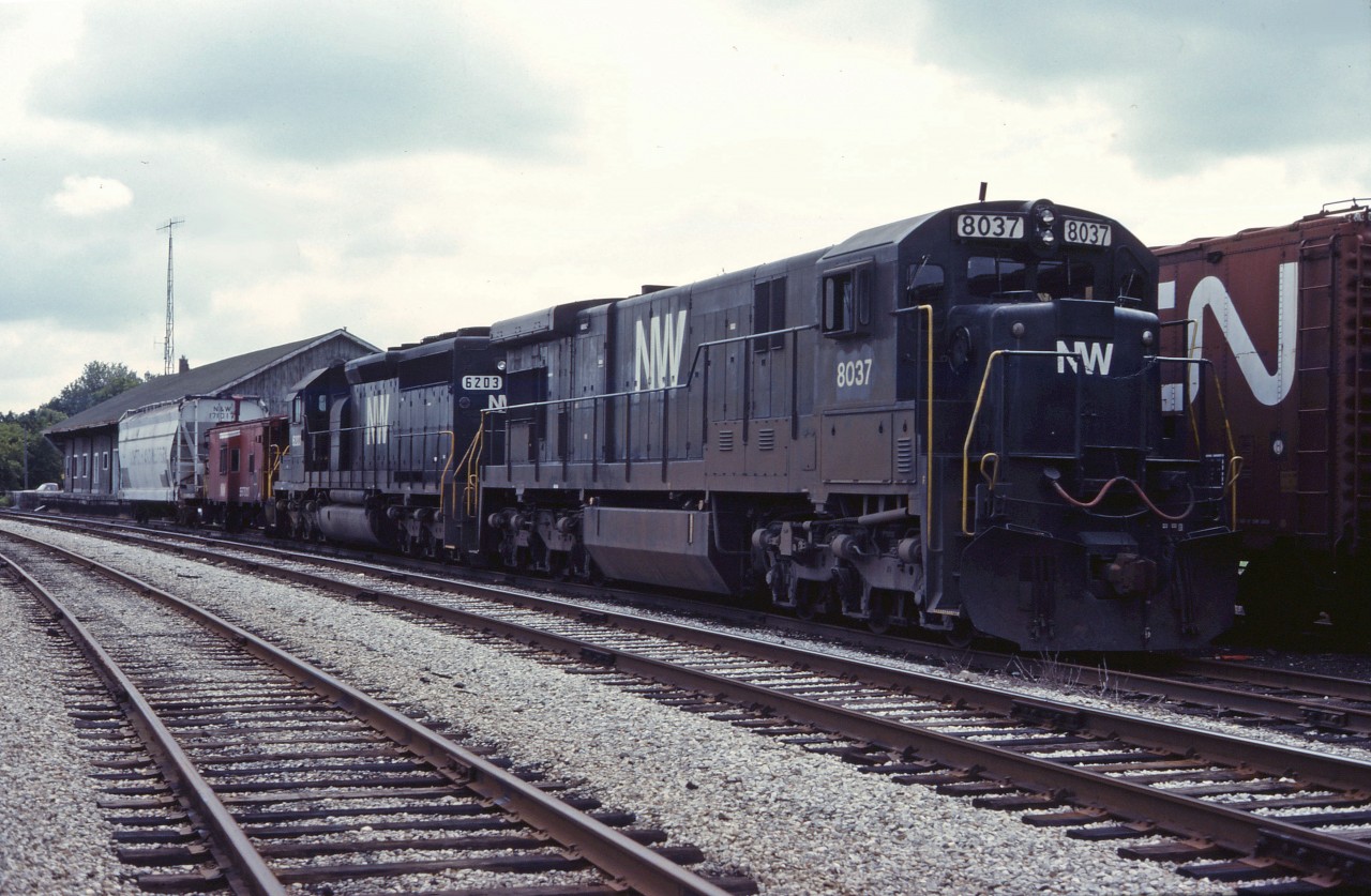 Two black Norfolk & Western units (C30-7 8037 and SD40-2 6203) sit outside the CN-NS "joint section" offices in St. Thomas in the fall of 1984.