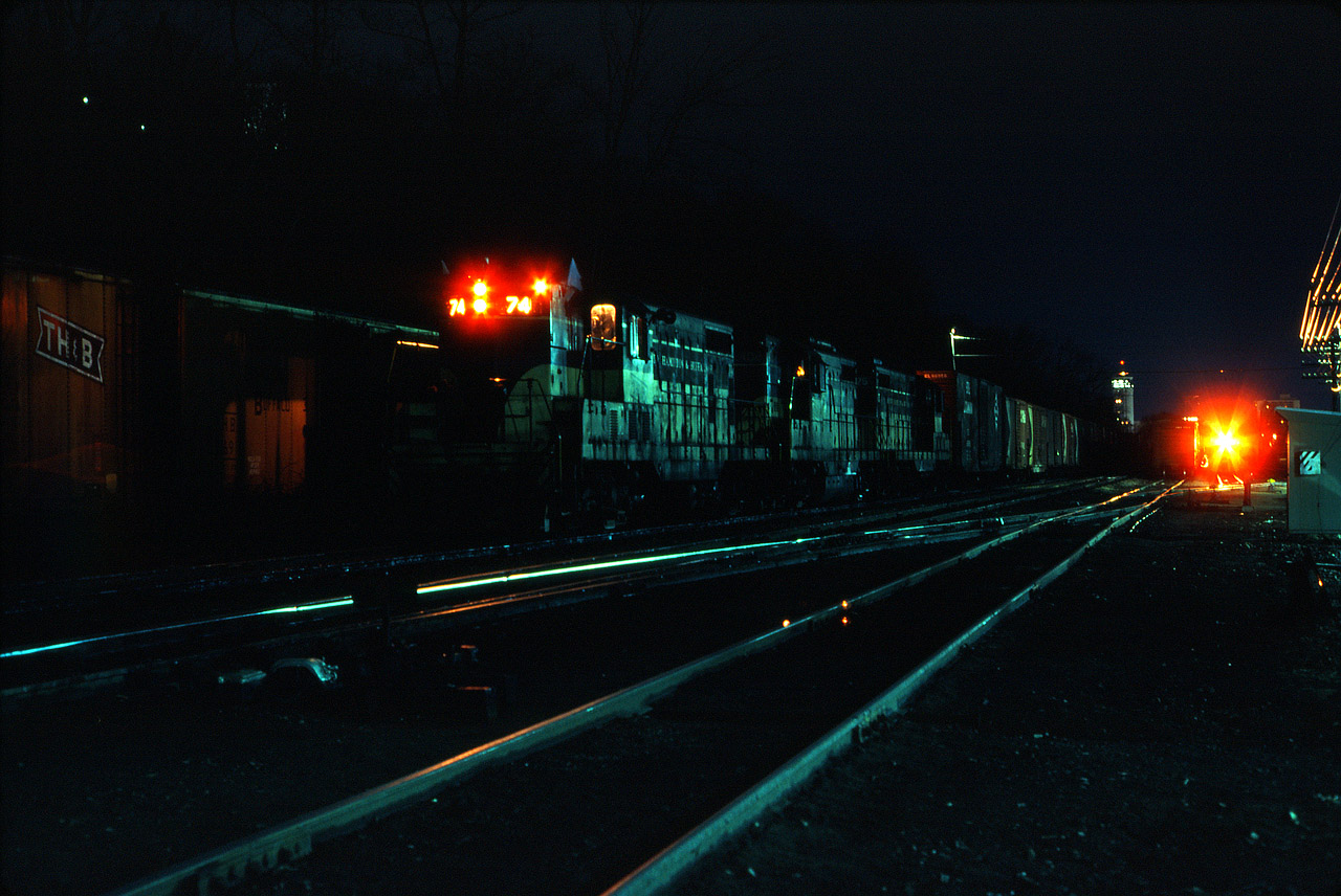 Run-through train TF2 pauses at Kinnear Yard in Hamilton to await the arrival of its counterpart from Buffalo's Frontier Yard. Once TF1 arrives, the CP crew which brought "the Kinnear" over from Agincourt will take that train to Toronto, while TF2 will continue its nocturnal trip to Penn Central rails. At the right, we see a TH&B yard engine--possibly bringing cars to connect with TF1 or FT2.