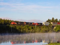 CN 2801 leads stack train Q120 as they rumble by Palmers Pond, at Dorchester, New Brunswick, at sunrise. 