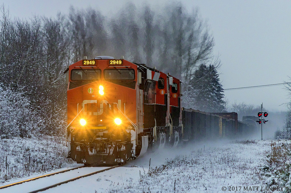 CN 2949 is leading train 406, as they head through Apohaqui, New Brunswick, the morning after a snowfall hit Southern New Brunswick. With not much light left in the day, the colors of the CN locomotion really stand out from the dreary snow covered backdrop.
