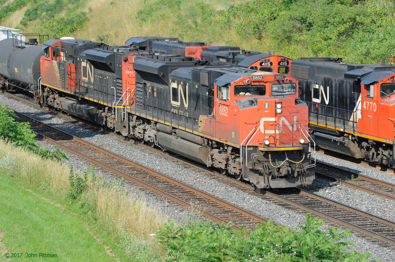 A matched set of SD70M-2's lead an eastbound CN freight train on track 2, past two GP38-2W and a GP9u pulling outbound Hamilton road switcher train CN 550 west along the Aldershot yard lead.  A total of 5 GMD built engines.  Train 550 will join the Oakville sub about a mile ahead at CN Snake, after the eastbound freight has cleared.  Mainline freight trains with all GMD power are the exception nowadays, though they still dominate in yards and road switching.