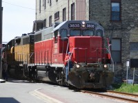 Squeezing through the buildings Goderich-Exeter Railway train X580 is seen approaching Regina Street in uptown Waterloo, Ontario with GEXR GP38AC 3835 and LLPX GP38AC 2210. The train is heading back to Kitchener from Elmira on the Waterloo Spur.