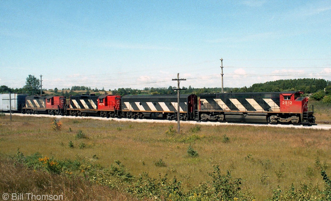 A mixed-bag lashup of CN M420 2512, F7Bu 9198, and GP9's 4579 and 4403 handle train #412, heading eastbound on the Guelph Sub east of Guelph in August 1984.