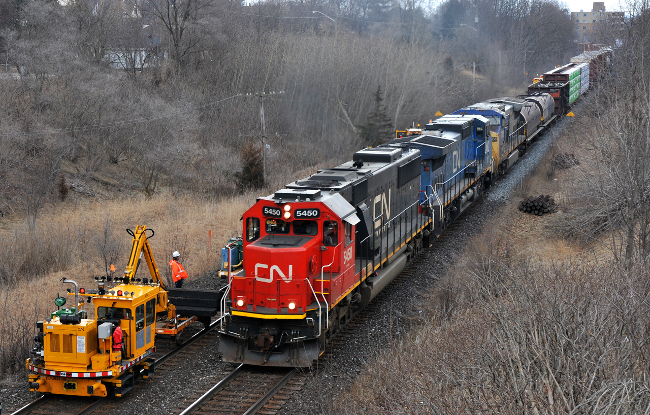 CN M38531 10 headed up the grade towards Hardy with CN 5450, IC 2462, GECX 7785, and 155 cars. The mega tie gang can be seen working on the north track