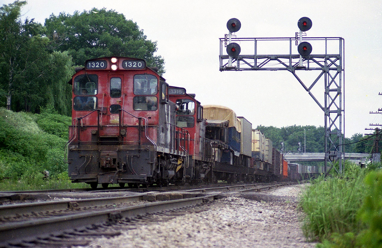 Rather obvious it has been a healthy summer so far as the lush foliage has really taken over at the Jct. It is still early July as a CN transfer heads into Hamilton behind CN 1320 and 1315, with 48 cars of all sorts of traffic in tow. Note the trailers; something we do not see any more........I recorded the caboose as CN 79768. Both motors (SW1200RS) went off roster in 1993.