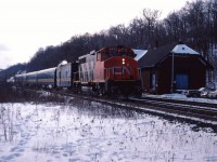 A four-car passenger train pauses a moment at the Dundas station in the winter of 1986. Steam for heating is provided by the steam generator unit and a leased CN GP40-2LW provides the power. In the mid-1980s, VIA leased CN GP40-2LWs and GP40 units to supplement its own aging fleet of 1950s cab units.
