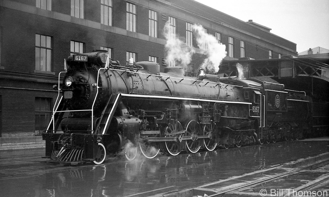 Steam on a rainy day: Canadian National 4-8-4 "Northern" 6167 waits along the wet platforms outside of Toronto's Union Station train shed, before heading out on an excursion in 1962.