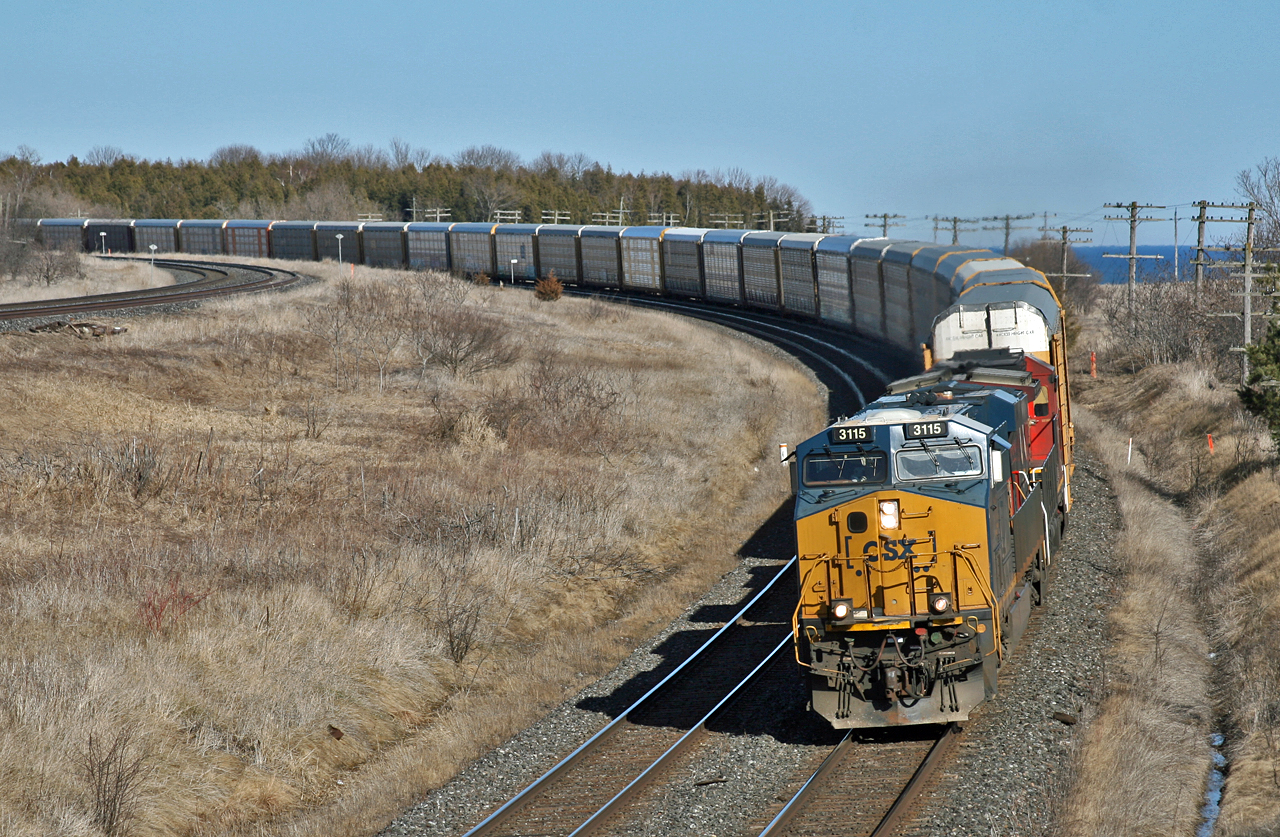 On one of the first nice days of spring, CN E 27121 20 eases around the curve at Lovekin, with CSXT 3115 and CN 2011 as they await a better signal on the approach to Clarke.