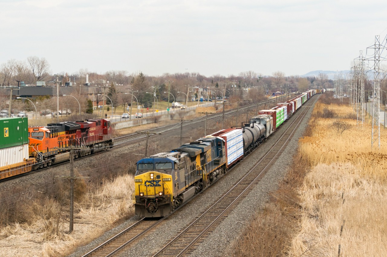 CN 327 with CSXT 532 & CSXT 5424 is heading west on CN's Kingston Sub just as CP 142 with CP 8803 & BNSF 3999 passes on CP's Vaudreuil Sub.