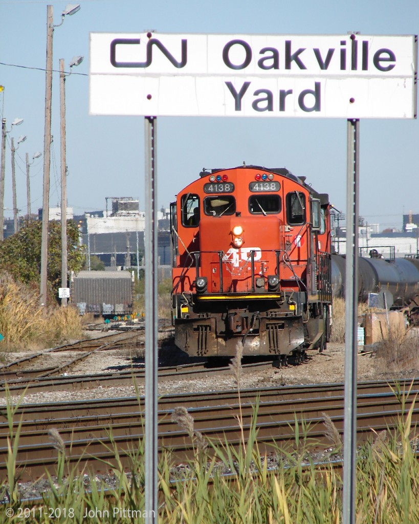 Working the yard, GP9u CN 4138 is still showing the "AR Illinois" logo it received for its role in 1997 movie "The Wrong Guy", which it continues to wear as of spring 2018.  The comedy movie can be found on youtube - the train scene begins around the 34 minute mark, for about a minute and a half of cinematic fame. 
This photo self-identifies its location, with the Ford Oakville plant in the background.  Does anyone recognize the location where "AR Illinois" 4138 and its train were filmed in the movie ?  From the movie point of view it's Illinois, but I think it was made in southern Ontario. 
CN 4138's Illinois connection foresaw CN's merger with IC that was announced in February 1998. It's quite often seen in Oakville or Aldershot yard, transfers and road switching along the Oakville sub.