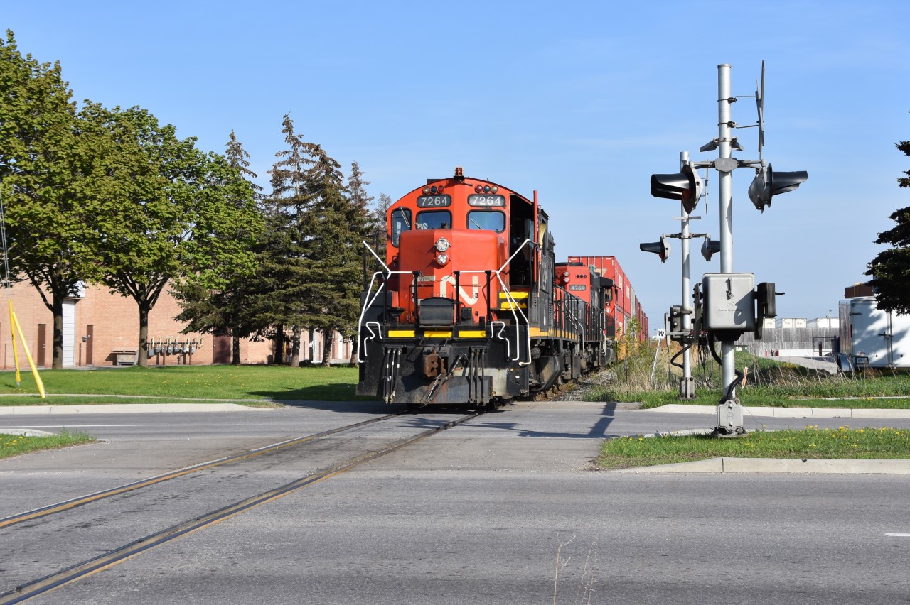 CN GP9RM 7264 is working the north end of BIT (Brampton Intermodel Terminal) on a sunny Wednesday evening. Behind them was a slug and a GP38-2W 4761. They have pulled the train ahead pausing right on the brig of the Williams Parkway crossing and within seconds they will reverse back into BIT as the crew at the other end would have thrown a switch so the train can back onto the right track for the containers to be unloaded.