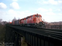 CP SD40 5535 and GP35 5013 head a westbound freight on the Belleville Sub, crossing the high bridge over the West Don River just east of Leaside and west of Donlands (junction with the CN Leaside Spur to Oriole). The trailing 5013 sports a unique version of CP's earlier 5" stripe scheme known as the "Ogden Multi" (with small multimark and stripes only going up 2/3 of the way). A nice cut of 40' boxcars makes up a good portion of the head end. <br><br> Visible in the background to the right is IBM's sprawling Don Mills headquarters, at 844 Don Mills Road / 1150 Eglinton Avenue East, which used to have a rail spur coming off the CP's Belleville Sub leading into one of the factory buildings (you can see the large roll-up doors from here). <br><br> <i>Mike Mastin photo, colour slide from the Dan Dell'Unto collection.</i>