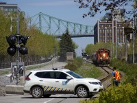 A Port of Montreal truck crosses one of the many crossings in this area, leapfrogging a slowly approaching train so that it can protect another crossing, as a transfer led by CN 7226 approaches. This will soon be rendered unnecessary by crossing gates, seen at left but not yet finished and in use.