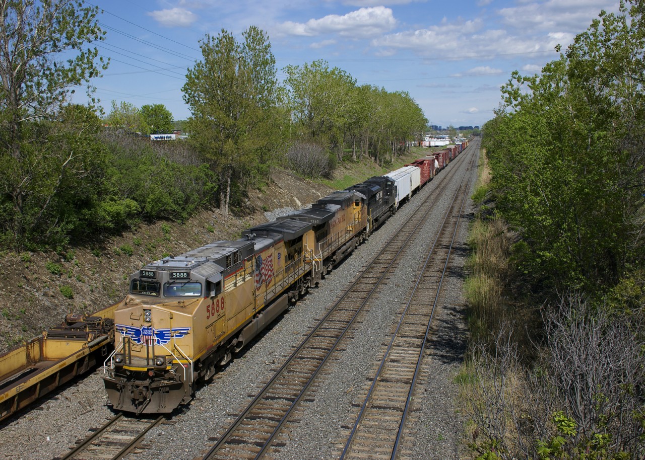 CN 529 has two UP units and one NS unit (UP 5888, UP 7265 & NS 1149) as it approaches its terminus of Taschereau Yard in Montreal. At left a long string of baretables are stored on the transfer track of CN's Montreal Sub.
