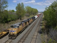 CN 529 has two UP units and one NS unit (UP 5888, UP 7265 & NS 1149) as it approaches its terminus of Taschereau Yard in Montreal. At left a long string of baretables are stored on the transfer track of CN's Montreal Sub.