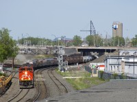 The classic signal bridge that CN 527 is passing under had two searchlight signals over each of the four tracks of CN's Montreal until last Tuesday; now searchlight signals are only found over the south and north track at Turcot West. A temporary pair of searchlights on a new, uncompleted signal bridge protect the freight track (second from left) and a temporary set of searchlight signals protect the transfer track (far left track), though that set is obscured by trees. Eventually all these signals will be replaced by 'vader' signals, which are already onsite and visible on the ground to the right of the exiting signals. Leading CN 527 is CN 8834, with a surprisingly clean nose. 