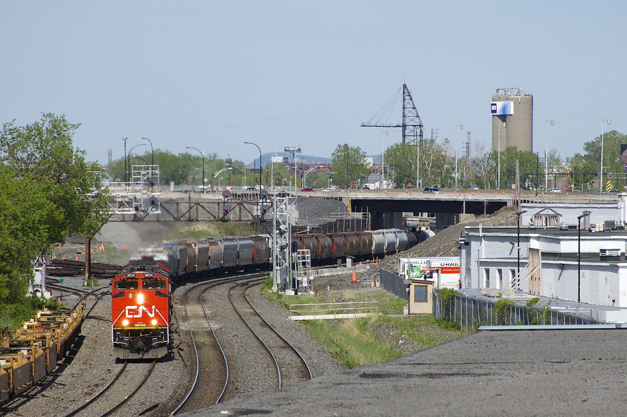 The classic signal bridge that CN 527 is passing under had two searchlight signals over each of the four tracks of CN's Montreal until last Tuesday; now searchlight signals are only found over the south and north track at Turcot West. A temporary pair of searchlights on a new, uncompleted signal bridge protect the freight track (second from left) and a temporary set of searchlight signals protect the transfer track (far left track), though that set is obscured by trees. Eventually all these signals will be replaced by 'vader' signals, which are already onsite and visible on the ground to the right of the exiting signals. Leading CN 527 is CN 8834, with a surprisingly clean nose.