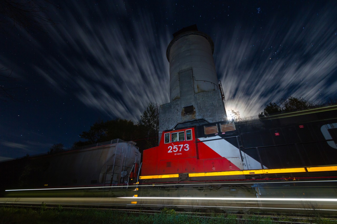 As the moon rises and clouds blur across the night sky, Canadian National G878 rolls past the ancient coaling tower in the sleepy town of Washago, Ontario. With G878 moving at a steady 15 M.P.H through town, the motion in this scene was both frozen by my external flash and accentuated by a 59 second exposure.

As some of you may know, today I launched a web series called Railway Ties! The series will explore various aspects of Canadian railroading, as told from the unique first-person perspective of the train. Coincidentally, the pilot episode entitled "Canada's Freight Train" features a scene from this  same location. After all, Washago has long been one of my favourite places to watch trains... 

To view the pilot episode of Railway Ties and see this familiar location under the cover of a late winter's snowstorm, click the following link:  https://www.youtube.com/watch?v=SJzDNKuVnp8