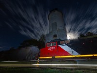 As the moon rises and clouds blur across the night sky, Canadian National G878 rolls past the ancient coaling tower in the sleepy town of Washago, Ontario. With G878 moving at a steady 15 M.P.H through town, the motion in this scene was both frozen by my external flash and accentuated by a 59 second exposure.

As some of you may know, today I launched a web series called Railway Ties! The series will explore various aspects of Canadian railroading, as told from the unique first-person perspective of the train. Coincidentally, the pilot episode entitled "Canada's Freight Train" features a scene from this  same location. After all, Washago has long been one of my favourite places to watch trains... 

To view the pilot episode of Railway Ties and see this familiar location under the cover of a late winter's snowstorm, click the following link: <a href=https://www.youtube.com/watch?v=SJzDNKuVnp8> https://www.youtube.com/watch?v=SJzDNKuVnp8 </a>