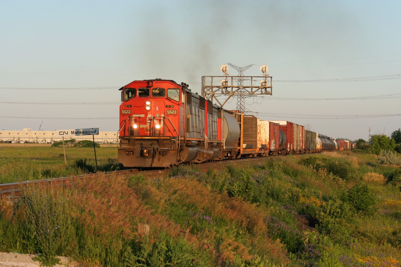 CN SD60F 5523 and a sister lead an eastbound manifest towards MacMillan yard in Toronto after meeting train 149 at Mansewood on the Halton Subdivision during a clear summer evening.