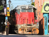 Squeezing through the buildings, Goderich-Exeter Railway (GEXR) train 584 is seen approaching King Street in uptown Waterloo, Ontario with GEXR GP38AC 3835 and LLPX GP38-2 2236. The train is heading north to Elmira from Kitchener on the Waterloo Spur. 