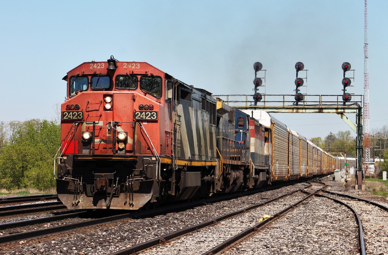 CN X397 passes under the old signal bridges in Paris, Ontario with a colourful lashup of cowls, lease power, and a fallen flag.