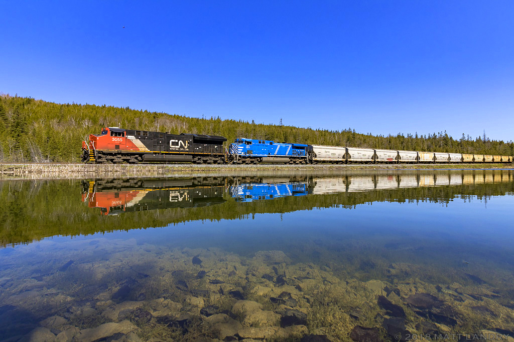 CN 3055, with a rare trailing unit(around here), CEFX 1011 powers potash train B730, as they head by a beautiful, "unnamed lake", as they start their descent down into their final destination of Saint John, New Brunswick, on a beauty of a Mothers Day morning.
