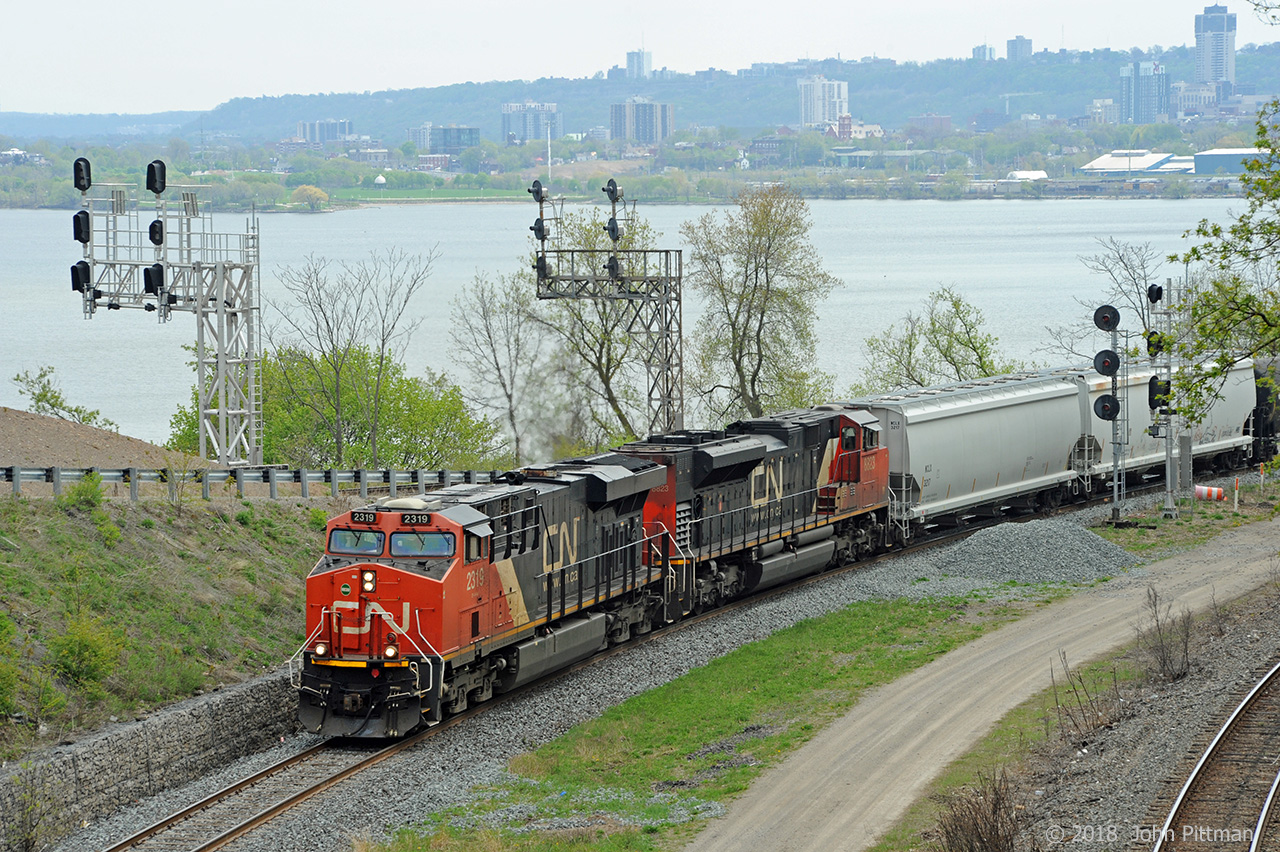 CN train 331 has entered its most characteristic section of track, the Cowpath, as it departs the eastbound Oakville Sub at Hamilton Junction, following this side of the wye to join the westbound Dundas Sub. CN 2319 is working hard while CN 8823 is taking it easy, apparently out of order and shut down.  On the far side of Burlington Bay the west end of Hamilton can be seen - at the right near the water is Stuart Street Yard which this train had passed a few minutes previously. 
Of interest are the old junction signals that continue in service, and the new signals that will eventually replace them. 
A group of us who regularly railfan in this area agreed Train 331 had not been heard of in a very long time; the word is that that it is reinstated.
