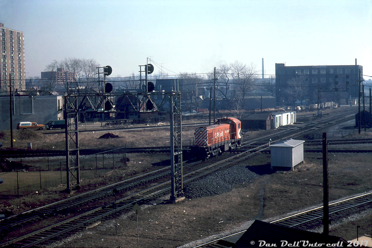 Morning at West Toronto: a lone CP S3 switcher, 6545, thumps over the West Toronto diamonds heading westbound on the North Toronto Sub back to Lambton Yard as light power. The tracks it's crossing are the CP MacTier-Galt Sub connecting track, and the double track mainline of the CN Weston Sub (since made into a grade separation for GO Transit/Metrolinx). The MacTier Sub can be seen curving eastward in the background to Osler Ave. behind the section houses.

When CP dieselized their yard operations in the 1940's and 1950's, they bought lots of 1000hp Alco/MLW S2 units, but eventually determined that the extra horsepower and turbocharger were not needed for yard duties and were an added maintenance expense. MLW produced a non-turbocharged 660hp S3 for CP to test, and before long they had switched to buying them in spades: eventually accumulating a fleet of over 100 of the little switchers for service across the railway (far outranking competitor GMD's SW8/900 model, of which CP only ordered 21).

In the Toronto area, S2 and S3 units were maintained out of John St. Roundhouse downtown (until it closed in the mid-80's and all the remaining 539-powered switchers retired), and saw service for decades working local freights, switching, and yard jobs out of Parkdale, West Toronto/Lambton, and Agincourt Yards. A few former CP S2 & S3 units have been preserved, notably S2 7020 at the TRHA museum downtown (ex-CPR John St. Roundhouse).

Mike Mastin photo, Dan Dell'Unto collection.